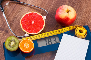 Electronic bathroom scale, centimeter and fresh fruits with stethoscope, slimming and healthy lifestyles
