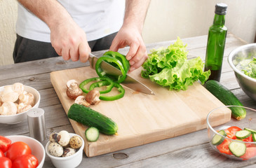 man prepares a salad of fresh vegetables