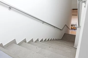 Abwaschbare Fototapete Treppen Treppe mit Geländer geht in einem neuen modernen Gebäude nach unten.
