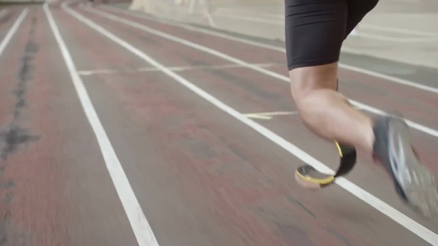 Follow Shot Of Amputee Runner With Prosthetic Leg Running On Track At Indoor Stadium In Slow Motion 