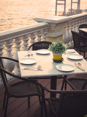 dinner table with artificial flower,plate,fork,spoon ,knife set beside river in color effect