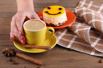 Yellow cup in the hands of women, a cake