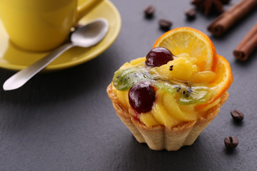 fruit cake with cherry, kiwi and oranges, a cup of coffee and ci