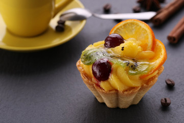 fruit cake with cherry, kiwi and oranges, a cup of coffee and ci