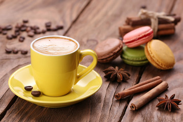 yellow cup of coffee, cinnamon and macaroon