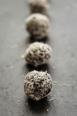 Homemade Healthy Paleo Raw Chocolate Truffles with Nuts, Dates and Coconut Flakes Put in Line, Vertical