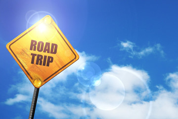 Yellow road sign with a blue sky and white clouds: roadtrip