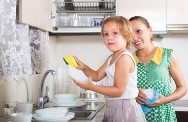 Girl helping mother washing dishes