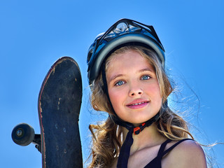 Girl sits in a skate park and girl holding a skateboard in hands. Close-up. Portrait of a teenager on the sky background. © Gennadiy Poznyakov
