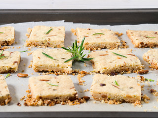 Cookies with rosemary, pignoli and pistachio nuts on baking parchment decorated with rosemary sprigs