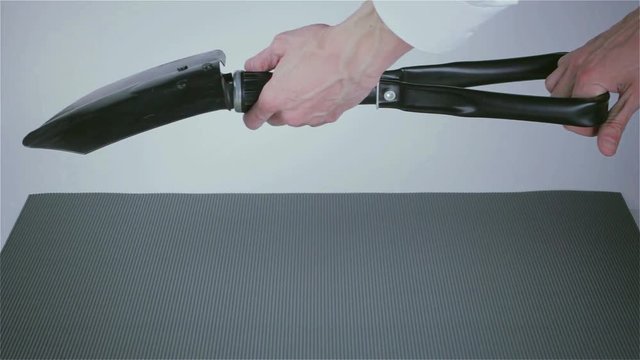 Black folding shovel in the hands of a businessman