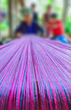 The close-up of many strand of cotton are threaded on a traditional loom