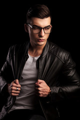 Obraz premium macho man in black leather wearing glasses while pulling jacket