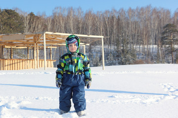 Fototapeta na wymiar Portrait of the little boy in a color jacket against snowin the winter 