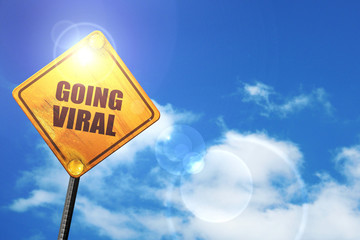 Yellow road sign with a blue sky and white clouds: going viral