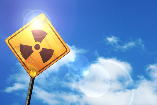 Yellow road sign with a blue sky and white clouds: Nuclear dange