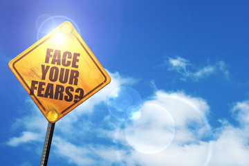 Yellow road sign with a blue sky and white clouds: face your fea