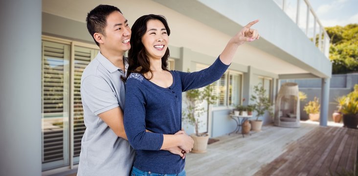 Composite image of happy couple with woman pointing up