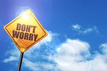 Yellow road sign with a blue sky and white clouds: don't worry