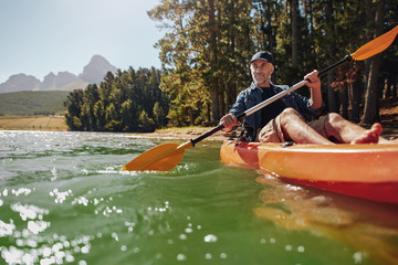 Mature man with enjoying kayaking in a lake - obrazy, fototapety, plakaty