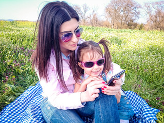 Young women with daughter on the phone on a sunny day outdoors