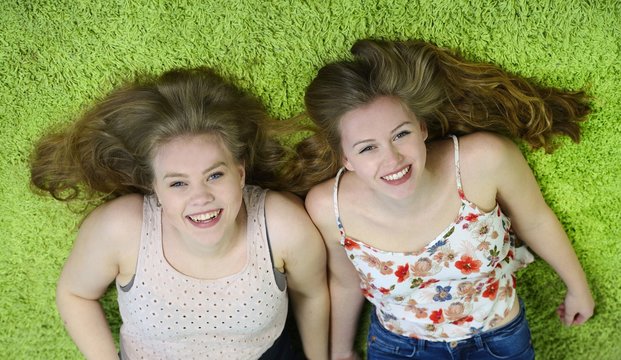 Jugendliche BFF leigen auf Teppich und lachen