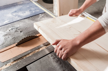 Carpenter working with Industrial tool in wood factory, circular blade with a wood board