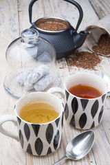 two cups 1 black tea rooibos and other fennel with teapot in the