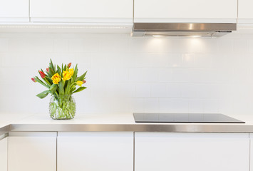 detail of a modern fancy kitchen with tulips in a vase on the sink