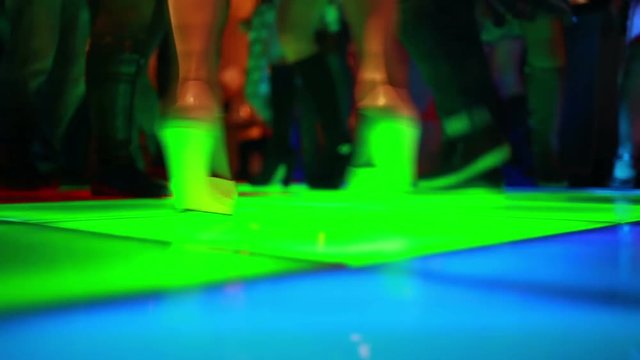 Colorful led dance floor with people dancing.