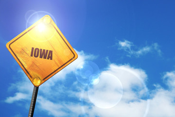 Yellow road sign with a blue sky and white clouds:  iowa