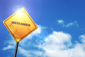 Yellow road sign with a blue sky and white clouds:  north dakota