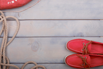 Red Boat shoes with orange laces near lifebuoy on light wood background close up