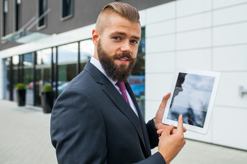 Fototapeta premium Young bearded businessman showing charts on tablet pc. Outdoor p