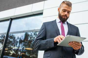 Young bearded businessman writting business e-mail using his tab