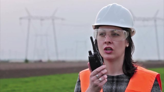 Businesswoman in hard-hat talking on walkie-talkie