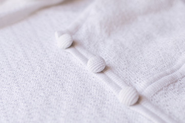 Buttons on white knitted dress, selective focus
