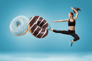 Fit young woman fighting off bad food on a blue background