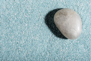 Fototapeta na wymiar Piedra sobre fondo de arena azul