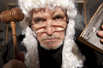  Old male judge in a courtroom striking the gavel