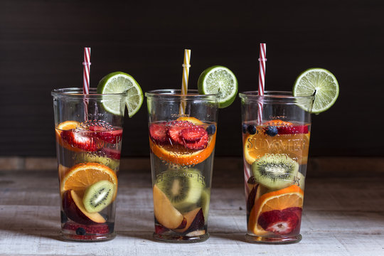 Detox water with fruit in glasses served in wooden tray. Rustic