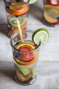 Detox water with fruit in glasses served in wooden tray. Rustic