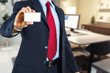 uomo in ufficio che mostra bigliettino da visita in mano