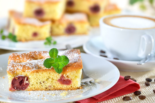 Frisch gebackener Kirschkuchen ( Blechkuchen mit versunkenen Sauerkirschen ) mit einer Tasse Cappuccino - Freshly baked cherry cake with a cup of cappucino