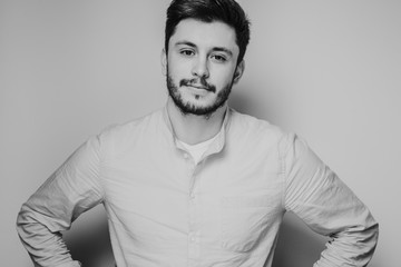 black and white portrait of handsome smiling man isolated on gray studio background posing to the camera