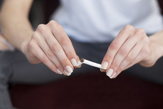 Close up of woman hands with broken cigarette. Stop smoking concept