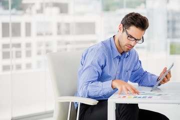 Businessman looking at document and using digital tablet
