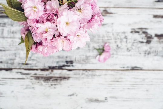 Branches of fruit tree in pink blossoms in vase on vintage wooden table