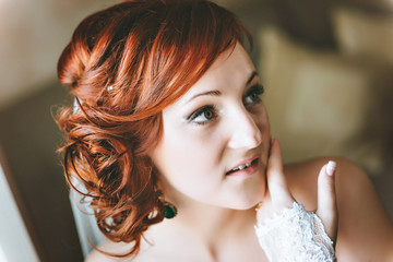 Fototapeta premium portrait of red-haired young bride, smiling, hand near the face