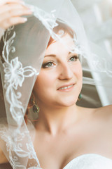 Portrait of young redheaded woman bride, through the wedding veil.